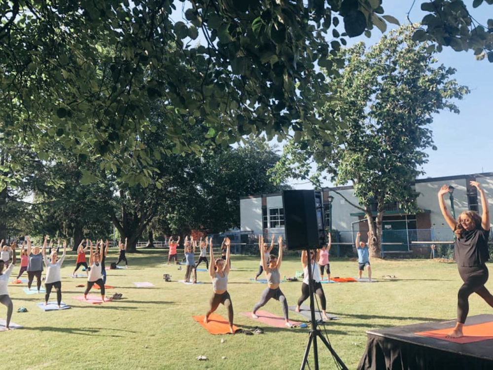 Photo of a large number of people doing yoga in a park