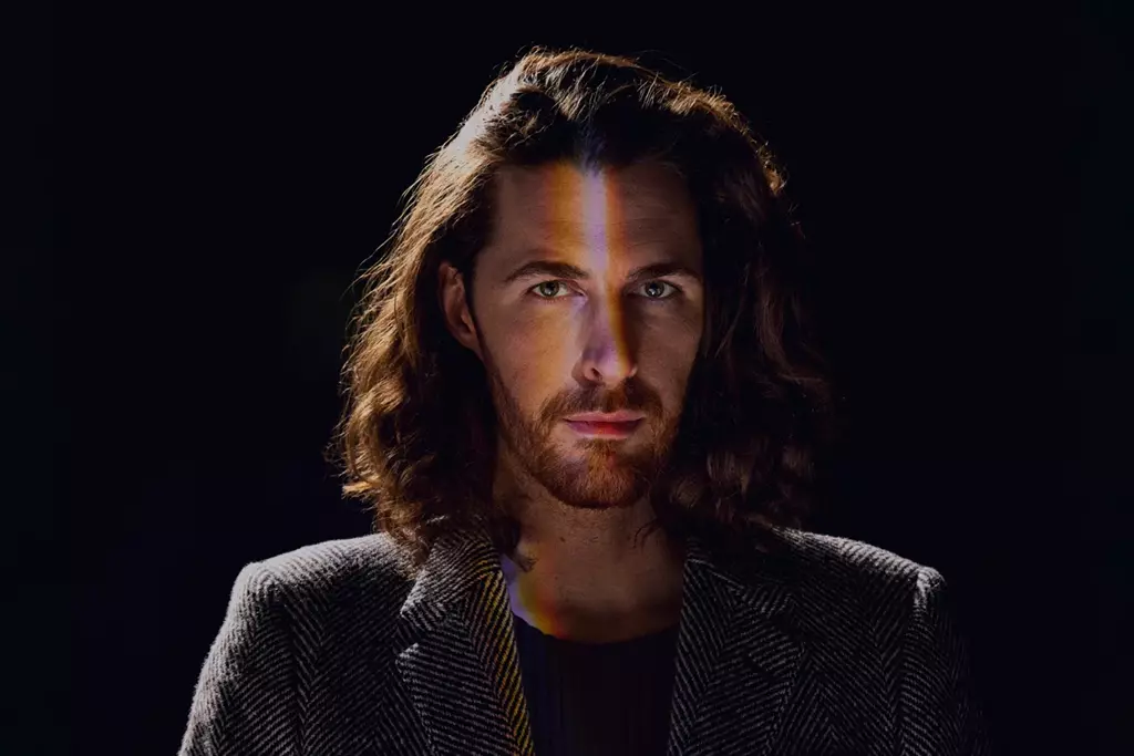 Photo portrait of Hozier, with a black background and a 