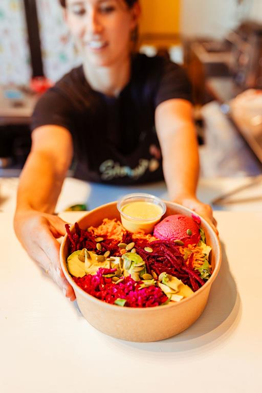 An employee holding a bowl of a plant based meal