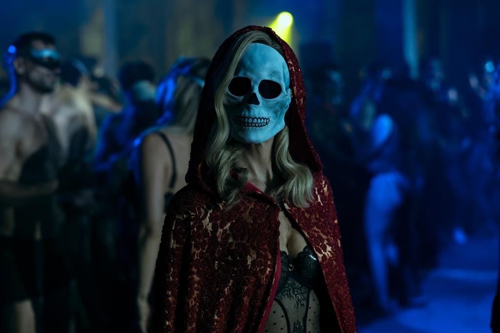 A women at a club wearing a skeleton mask and a red cloak