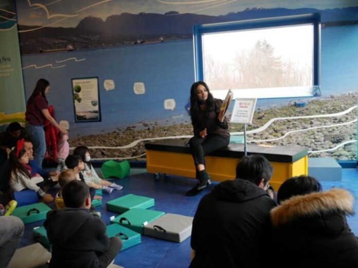 An image of a woman reading a book in a library to children