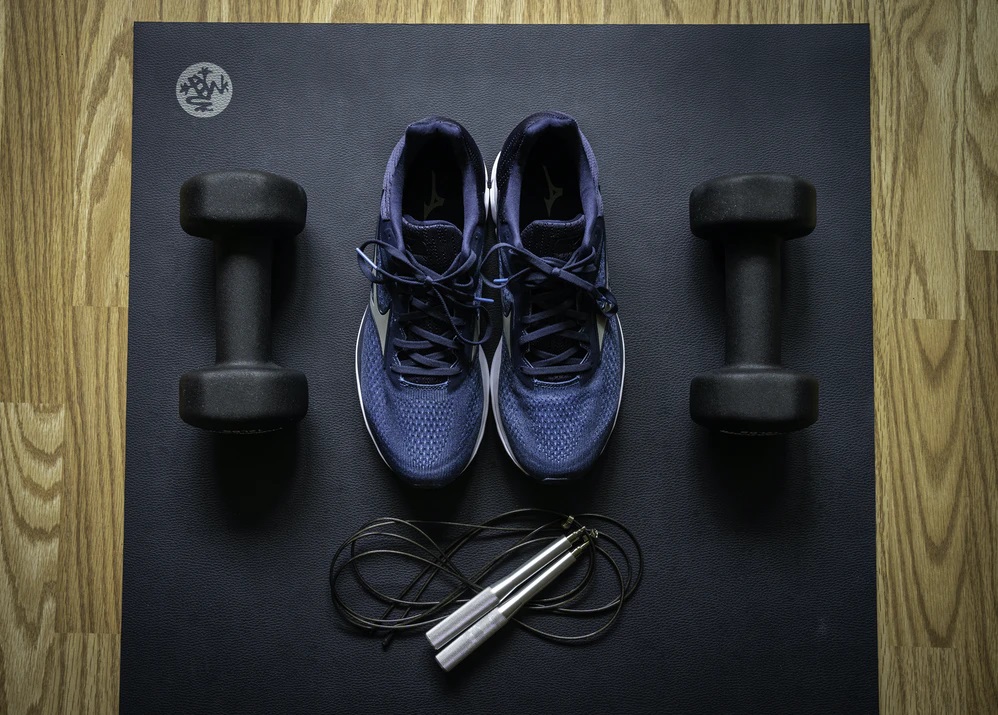 Photo of athletic shoes and weights next to a jump rope