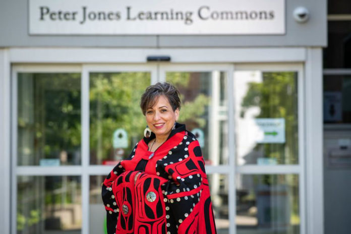 Photo of Camille Callison standing outside the Peter Jones Learning Commons sign at UFV Abbotsford's library.
