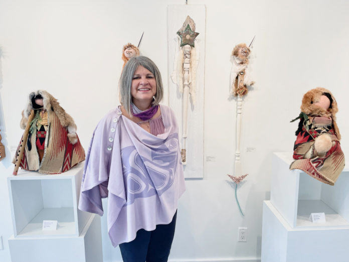 Photo of Karen Goodfellow at the opening of her art exhibition, surrounded by her work.