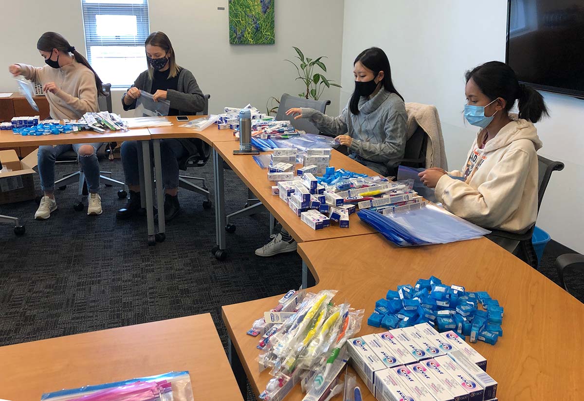 Photo of the UFV pre-dental club's executives assembling kits with dental hygiene supplies