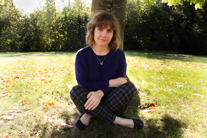 Photo of Julia Dovey sitting cross-legged in front of a tree