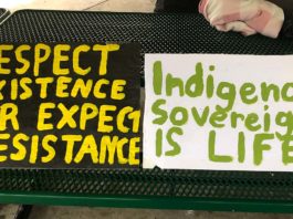 Two protest signs. One reads "respect existence or expect resistance" and the other reads "Indigenous soverignty is life"