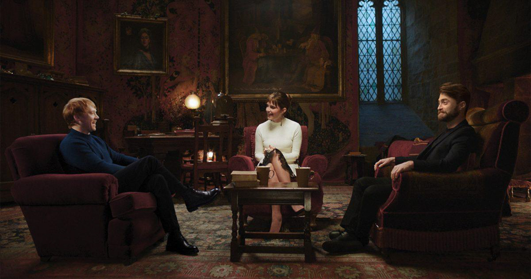 Screenshot from Harry Potter 20th Anniversary Special showing Rupert Grint, Emma Watson, and Daniel Radcliff speaking on a Hogwarts set