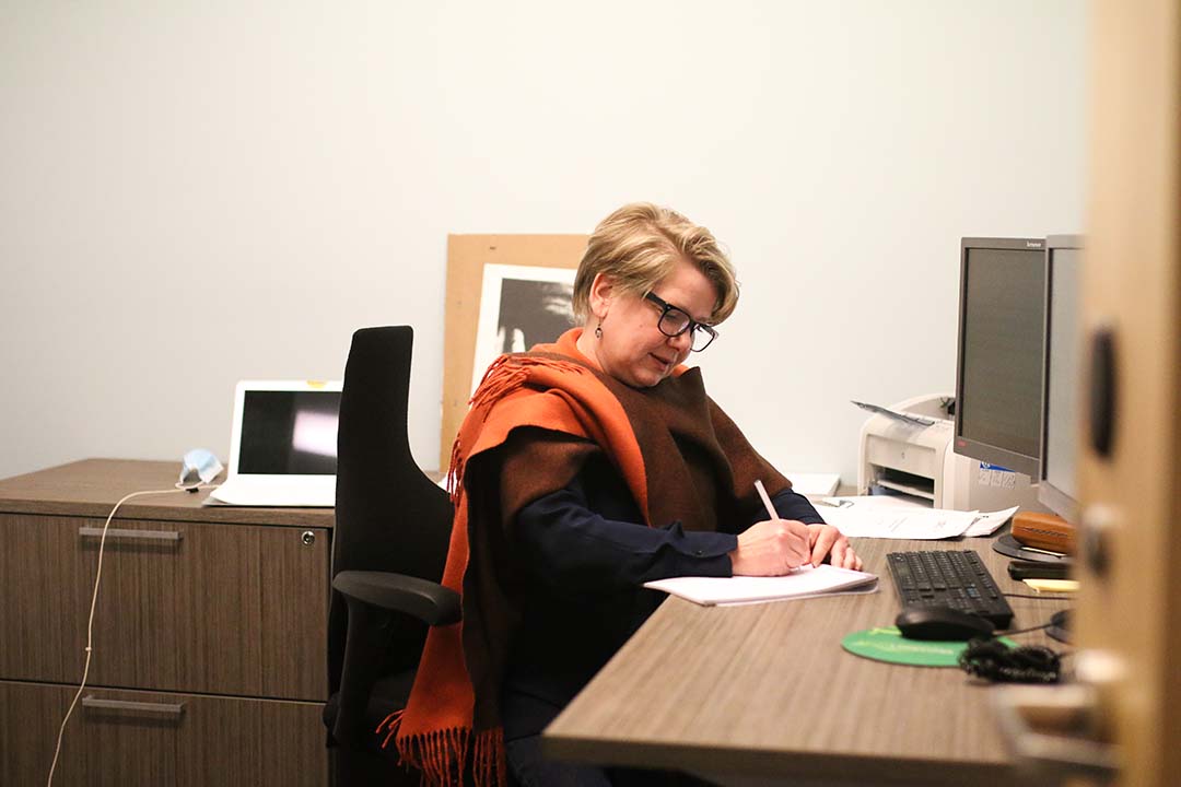 Photo of Kim Nickel wrting at her desk