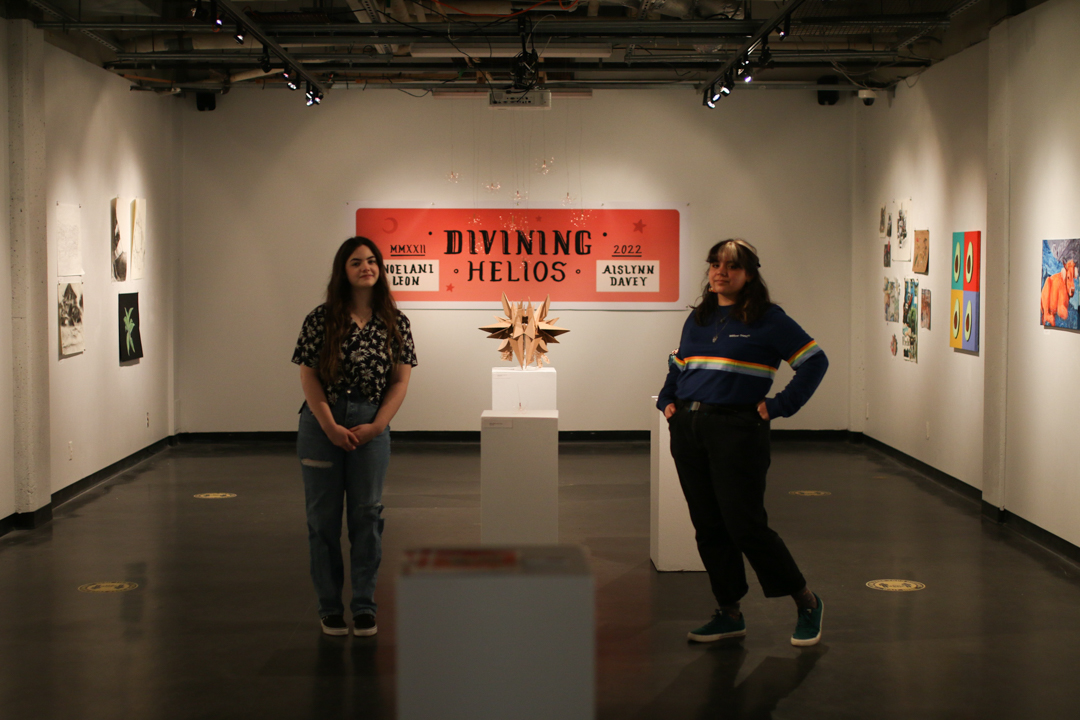 Photo of Noelani Leon and Aislynn Davey surrounded by the art in their exhibition