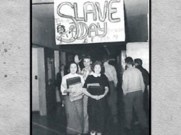 Historical photo of students walking in a hall at Chilliwack highschool in 1950s, with a large sign overhead that reads "Slave Day."