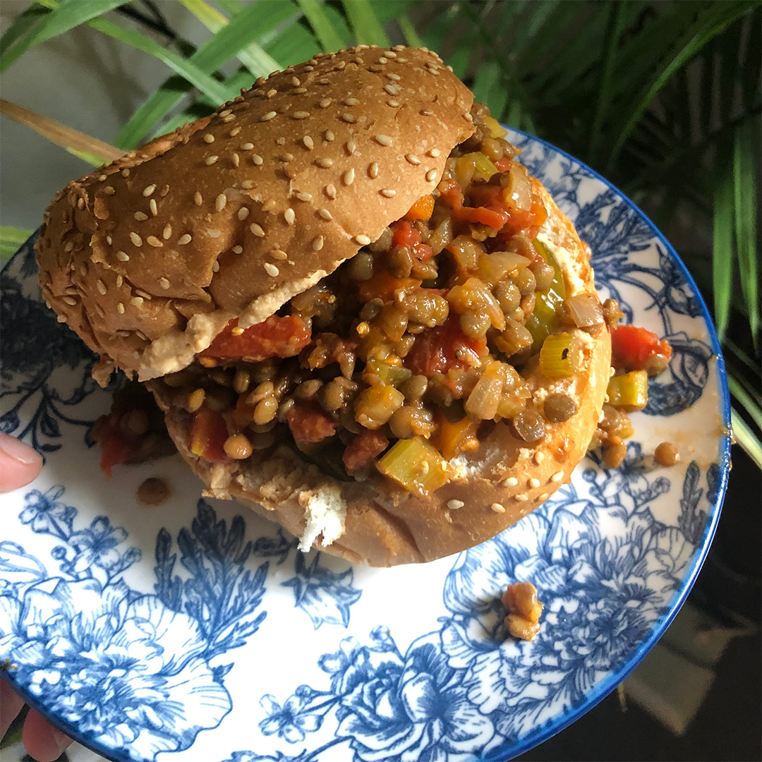Photo of a bun filled with lentils and other vegetables in a sauce