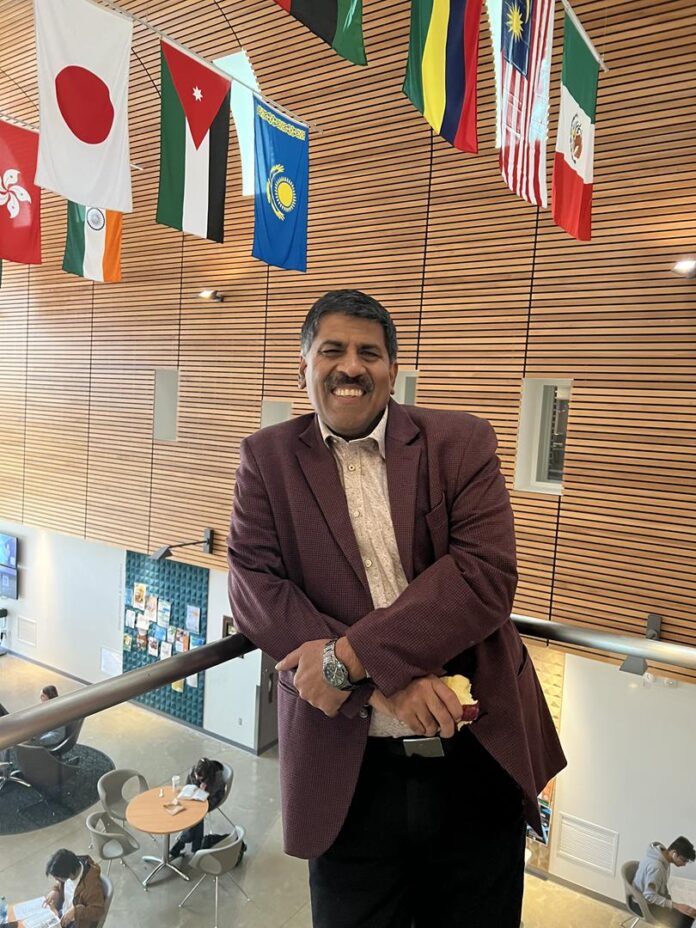 Professor Rajnish Dhawan standing on the second floor of the SUB building on the UFV campus. He is smiling.