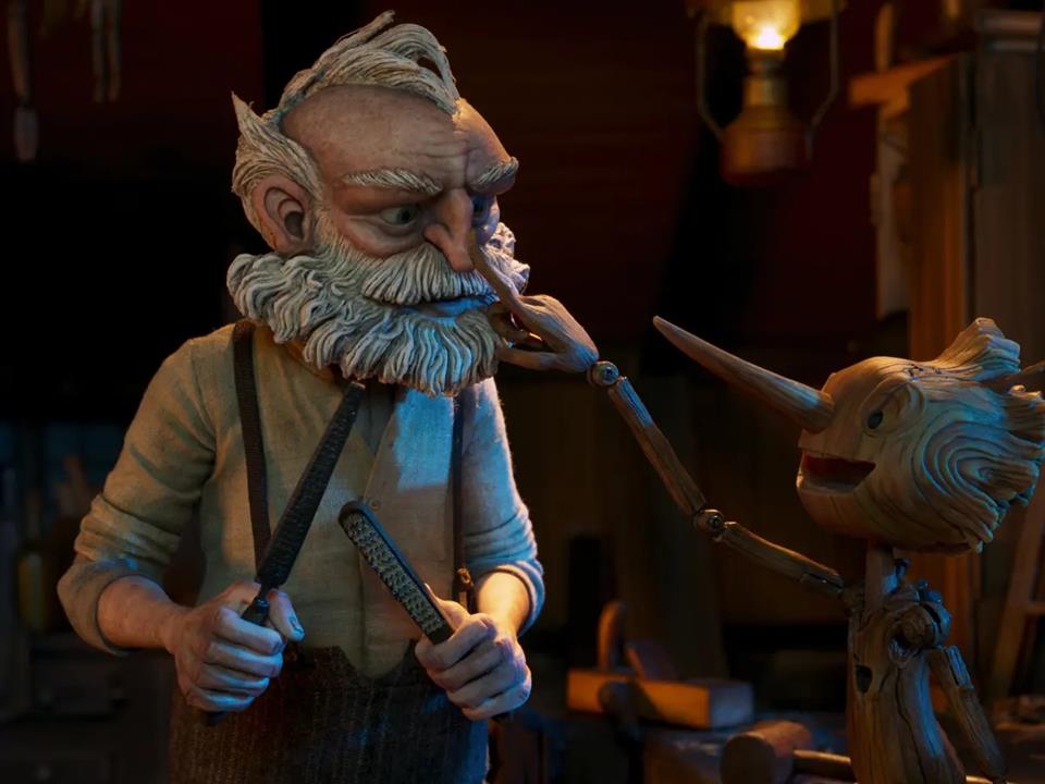 The animated characters pinocchio and Geppeto stand in the workshop. Pinocchio is smilling and placing his finger on Gepeto's nose. Gepetto looks annoyed.