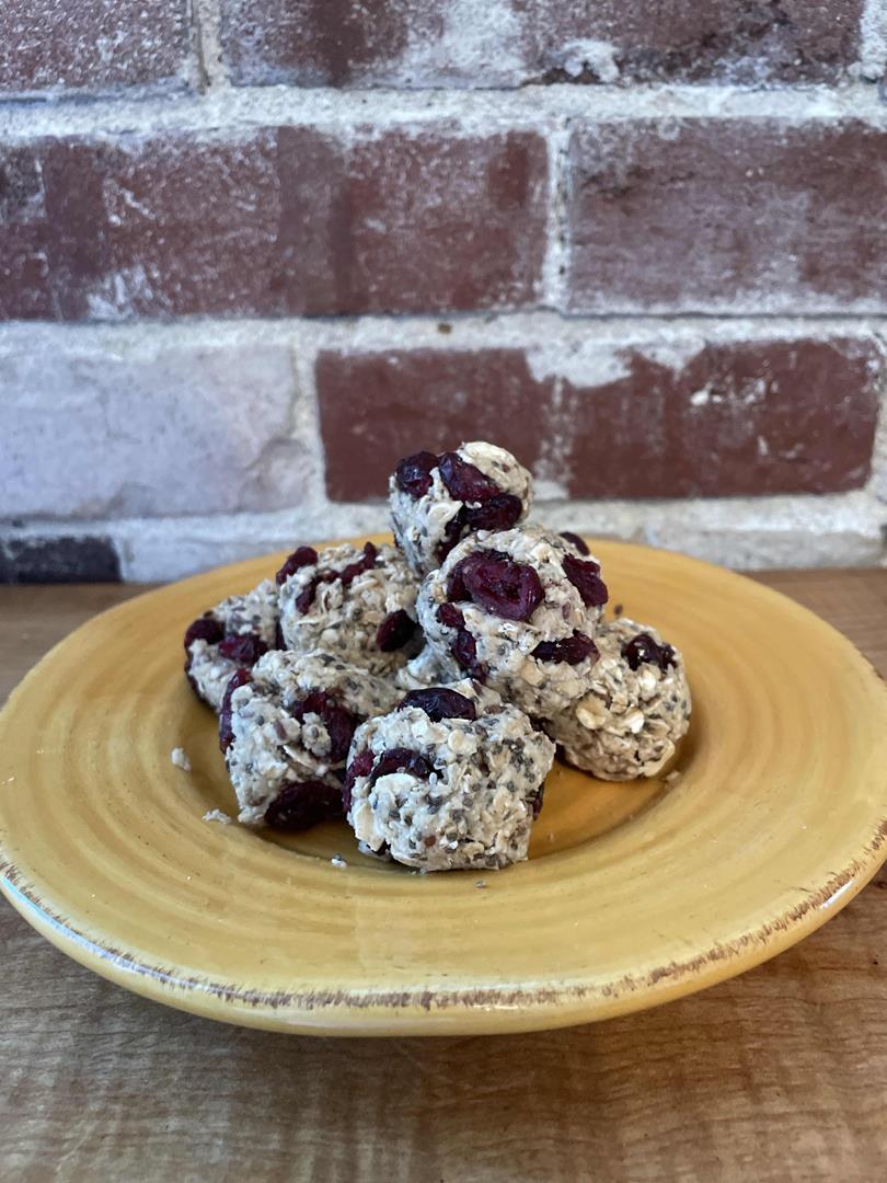 A photos of oatmeal energy balls piled on a yellow plate in front of a brick wall