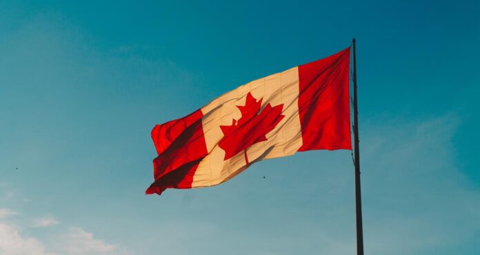 The canadian flag flies on a blue sky background