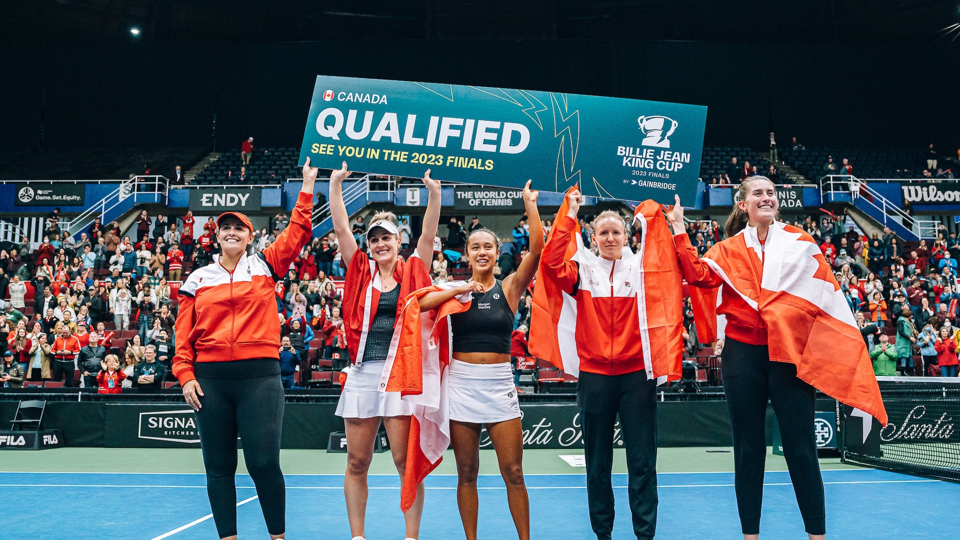 Leyla Fernandez and the rest of Team Canada hold up a victor's banner as Team Canada moves on to the Billie Jean King Cup Finals in November