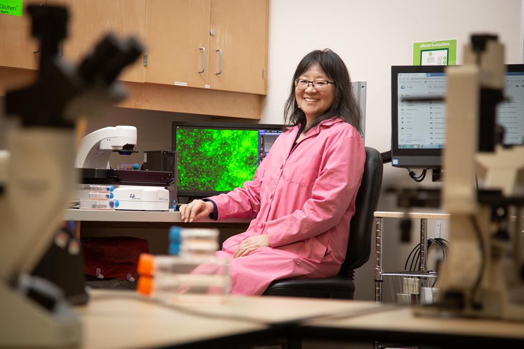 Dr. Lee sits in her office, she is wearing a pink top and is smiling
