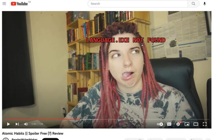 A screen grab of ReaderWriterMaker's Youtube channel from a recent video. She is making a face with her tounge out and red text over lays her face saying "Language exe. not found".