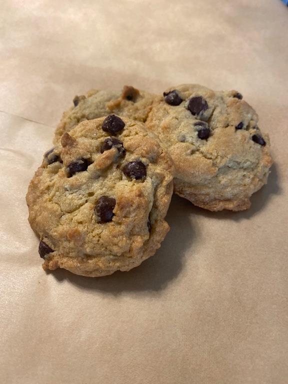 Three chocolate chip cookies placed on top of parchment