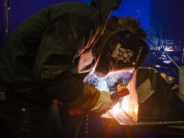 A student welding a piece of metal equipped with safety attire