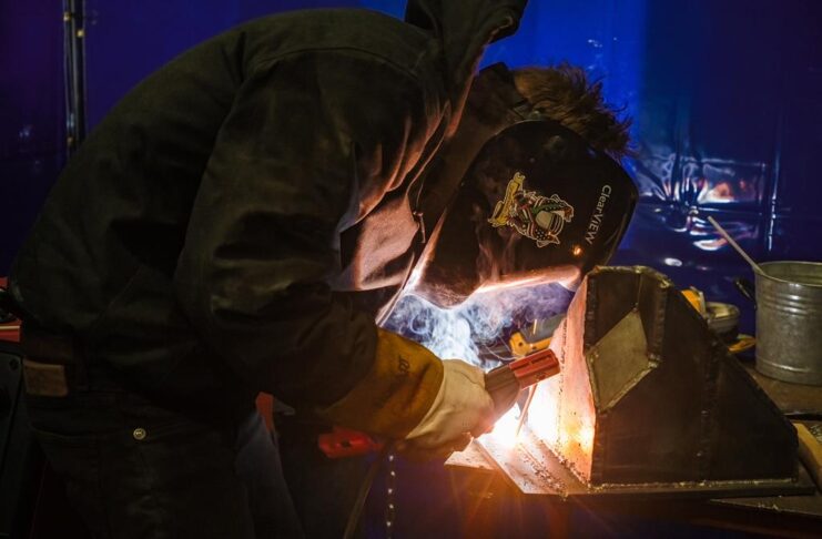 A student welding a piece of metal equipped with safety attire