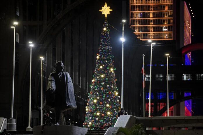 A statue of the Latin American hero, Simón Bolívar, is seen in front of a Christmas tree in downtown Caracas