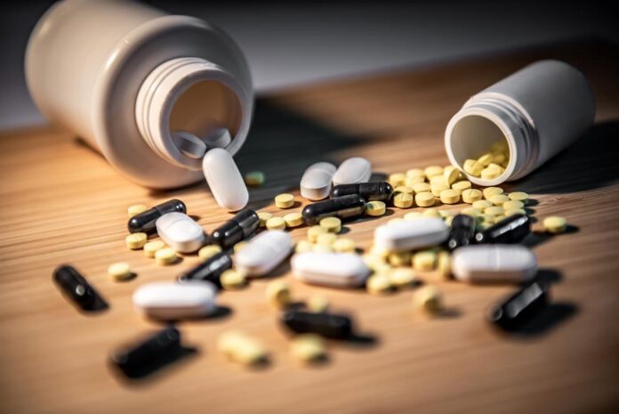 Pills spilling out of pill bottles on wooden table. Prescription medicine and medical treatment concepts