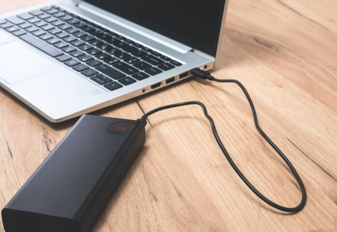 Power bank with usb-c cable is charging laptop . Modern, information technology.